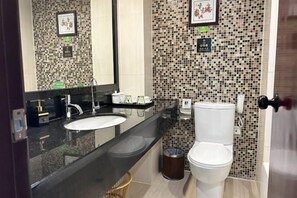 Un baño con lavamanos, inodoro y espejo.