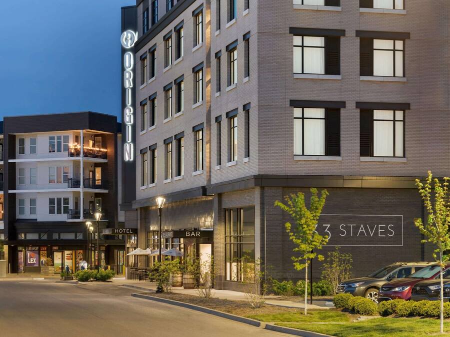 Un hotel con bar y restaurante en la planta baja, un cartel que indica '3 Staves', y un estacionamiento con automóviles.
