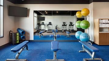 A gym with exercise equipment, benches, and exercise balls.