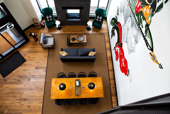Un salon moderne avec un canapé, une table basse et des fauteuils disposés autour d’une table en bois. On aperçoit une cheminée au fond.