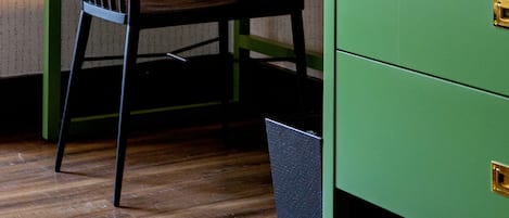 Un bureau vert avec une chaise noire, une lampe et un tableau d’affichage en liège où sont accrochées des notes et une petite plante.