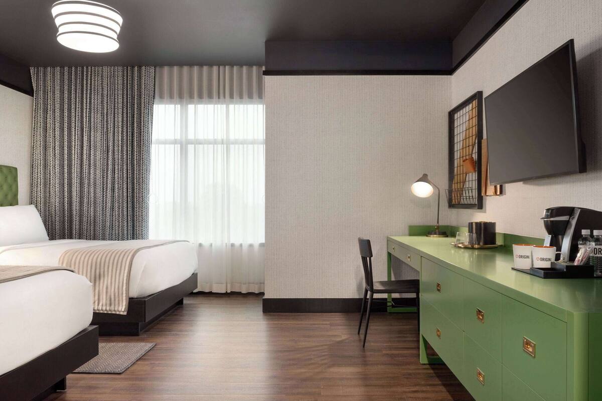 A hotel room with a bed, a desk, a chair, a television, and a coffee machine.