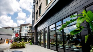 A hotel with a modern facade, large windows, and a stop sign in front. - Origin Lexington a Wyndham Hotel (Lexington)