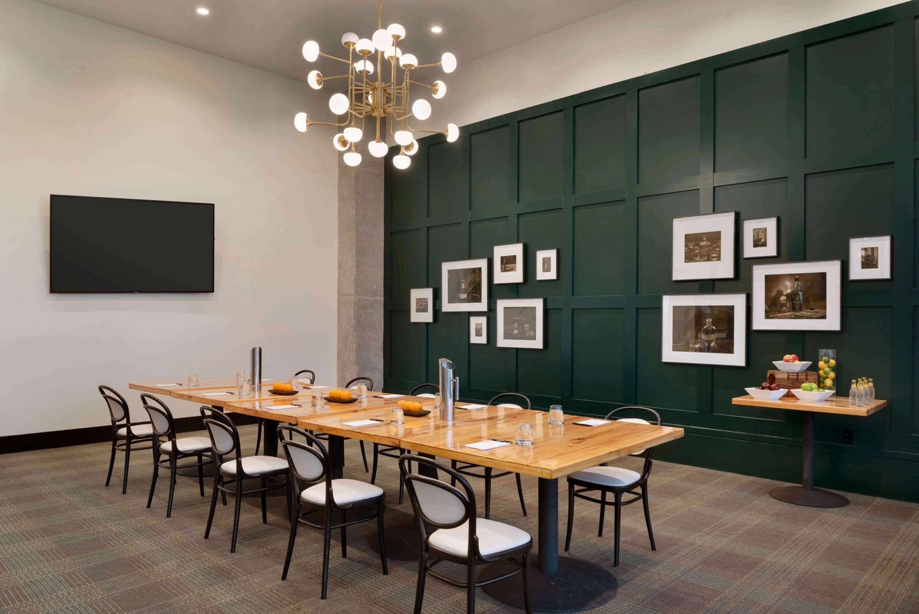 A conference room with a long table, chairs, a projector, and a wall-mounted screen.
