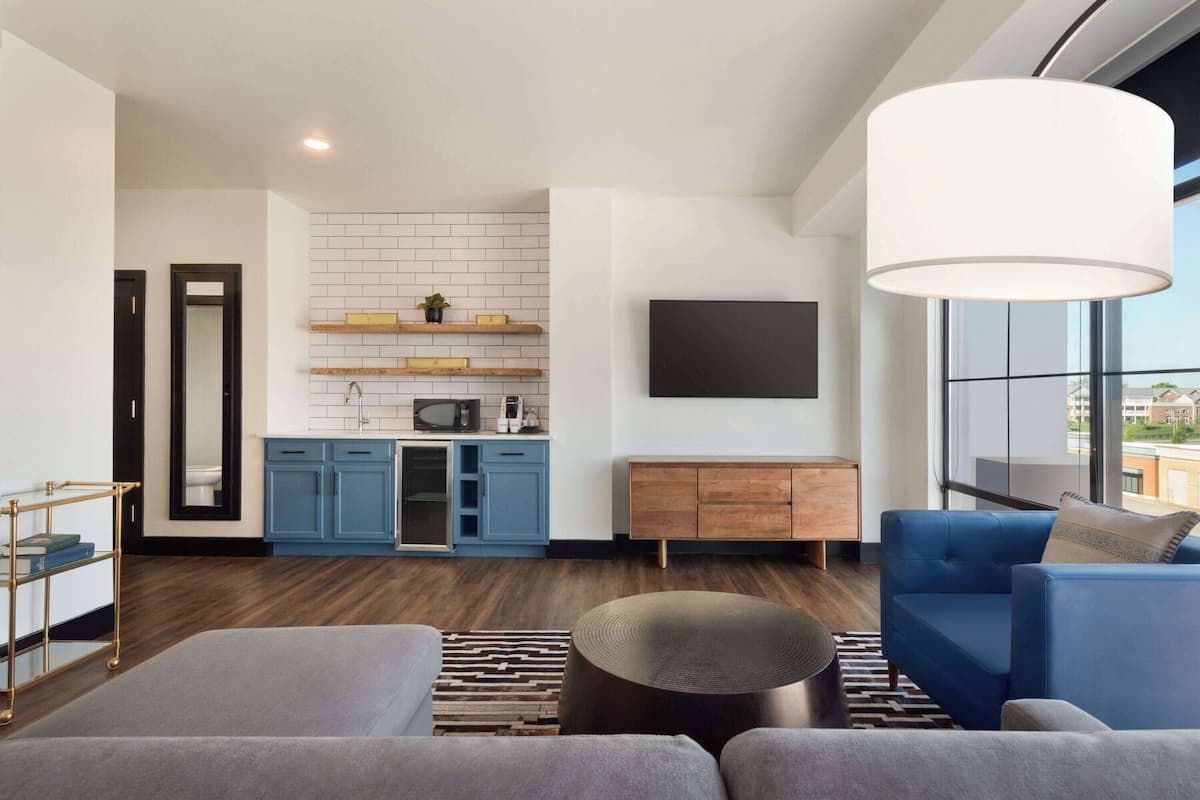 A modern living room with a blue sofa, a grey rug, and a wooden coffee table.