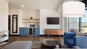 Un salón moderno con un sofá azul, una alfombra gris y una mesa de centro de madera.