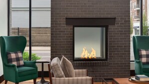 A modern living room with a fireplace, green armchairs, and a plaid sofa. - Origin Lexington a Wyndham Hotel (Lexington)