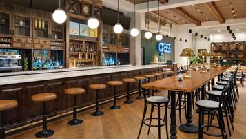 A bar area with wooden bar stools, a long counter, and a neon sign reading "grass".