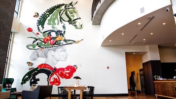A spacious lobby with a large mural, a reception desk, and seating areas.