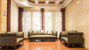 A lobby with a sofa, two armchairs, and a large window with curtains. - Jinchang Hotel (Shaoxing)