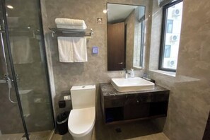 Une salle de bain moderne avec une douche à parois de verre, des toilettes blanches, un meuble-lavabo en marbre et un grand miroir.