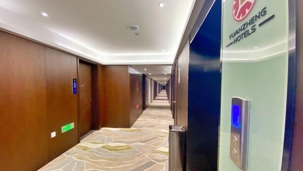 A hotel corridor with a patterned carpet, wooden walls, and a sign for Yanzheng Hotels. - Yuanzheng Hotels (Hangzhou)