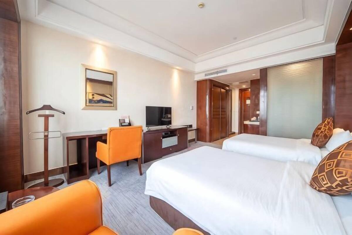 A hotel room with a bed, a desk with a chair, a television, and a mirror.