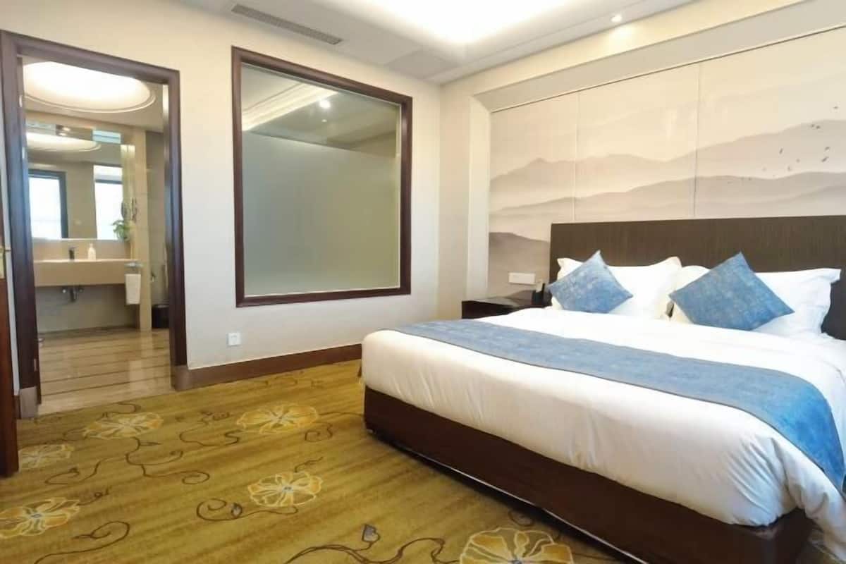 A hotel room with a large bed, a mirror, and a view of the mountains.