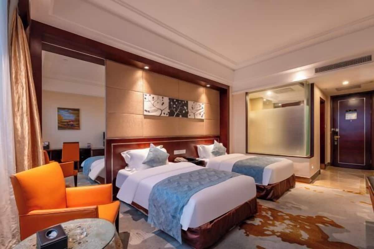 A hotel room with two beds, a sofa, a small table, and a large mirror.