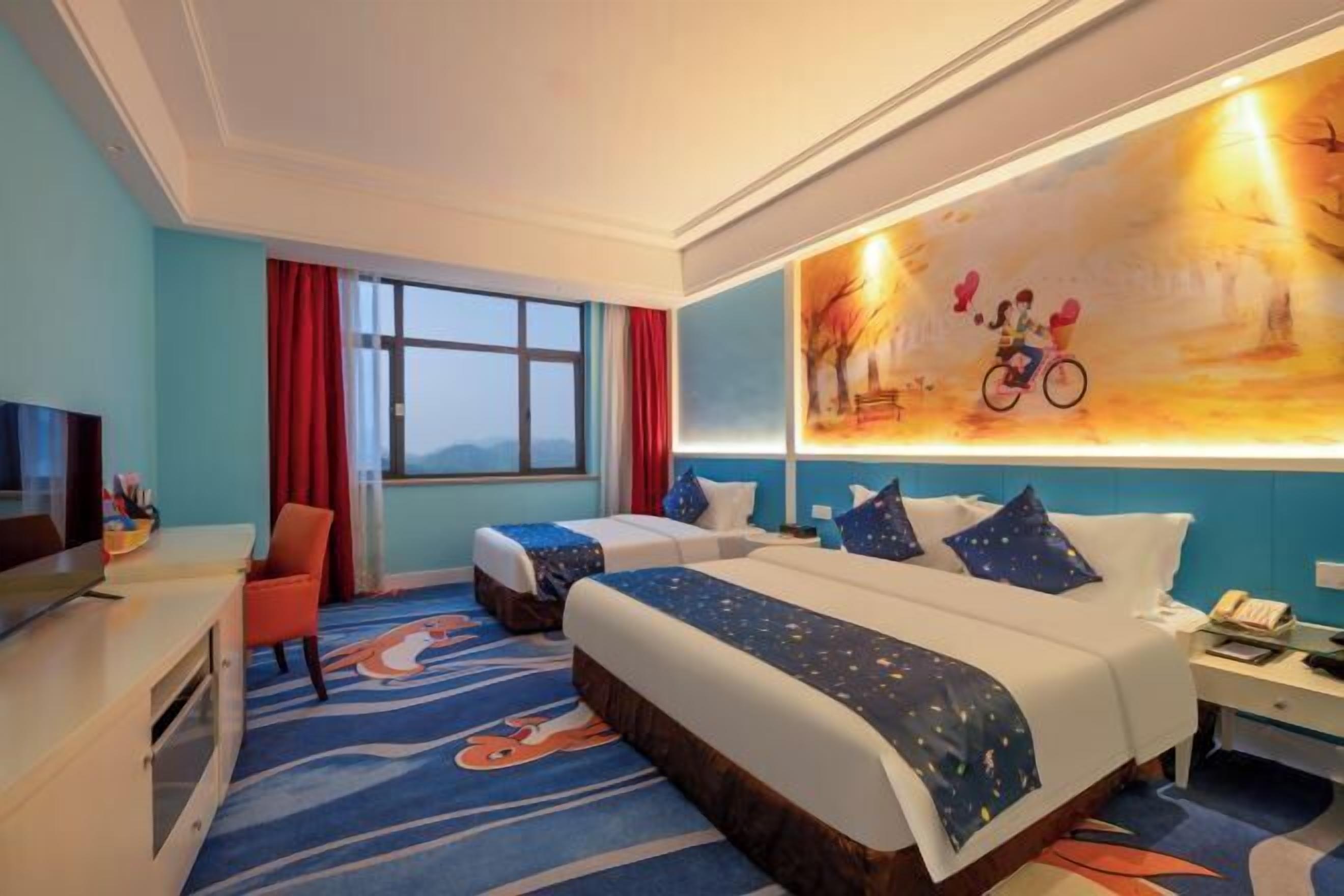 A hotel room with two beds, a TV, a desk, and a large window.