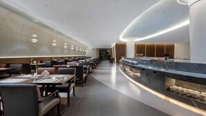 A modern restaurant with a long counter, multiple tables, and a sleek, curved ceiling design. - Hailiang Business Hotel (Zhuji)