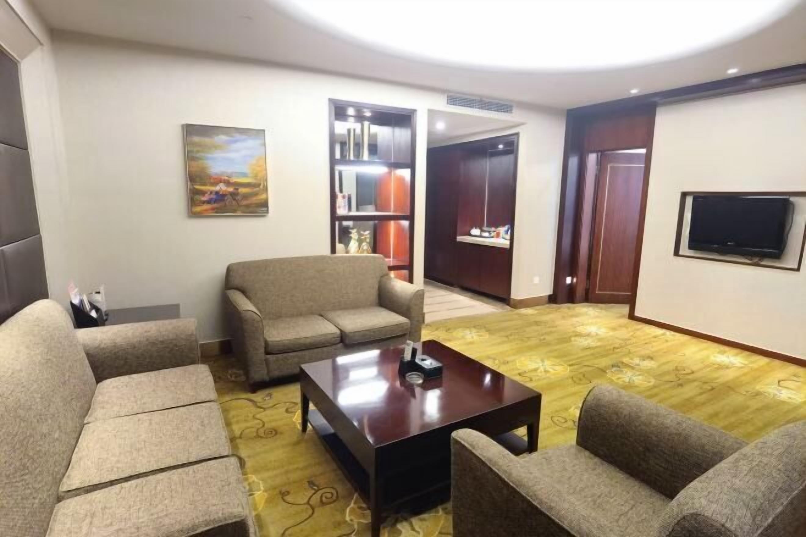 A living room with a sofa set, a coffee table, a TV, and a bookshelf.
