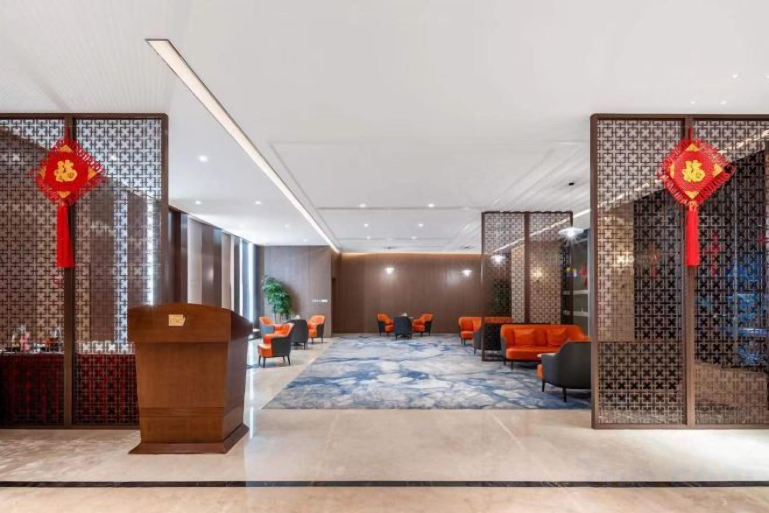 A hotel lobby with a reception desk, seating area, and decorative elements.