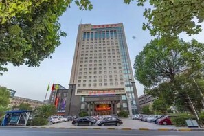 A multi-story hotel with a prominent entrance and a parking lot in front. - Hailiang Business Hotel (Zhuji)