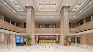 A spacious lobby with high ceilings, large columns, and a central art piece. - Hailiang Business Hotel (Zhuji)