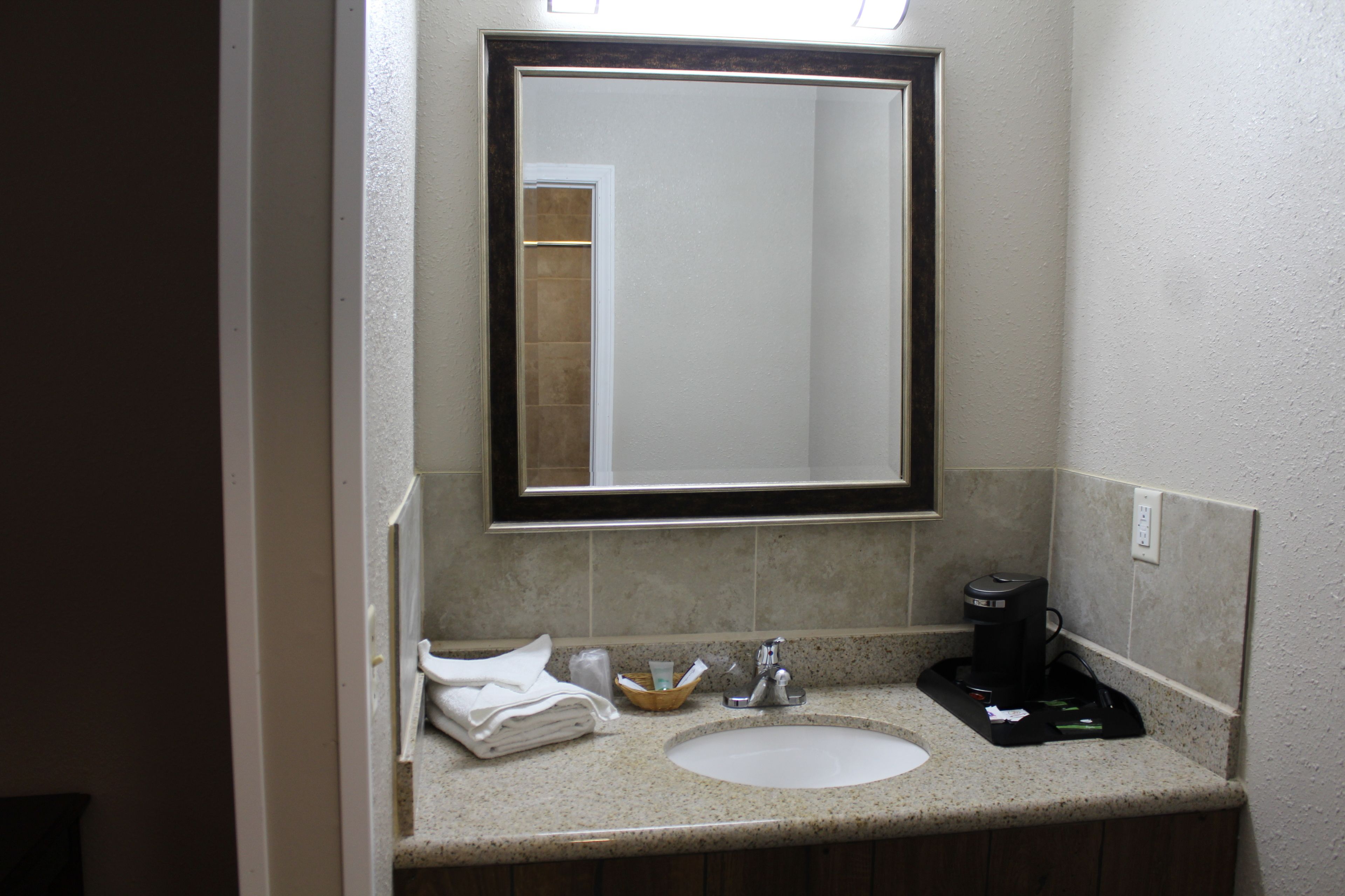 Un bagno con lavandino, specchio e articoli da toilette.