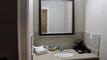 Un bagno con lavandino, specchio e articoli da toilette.
