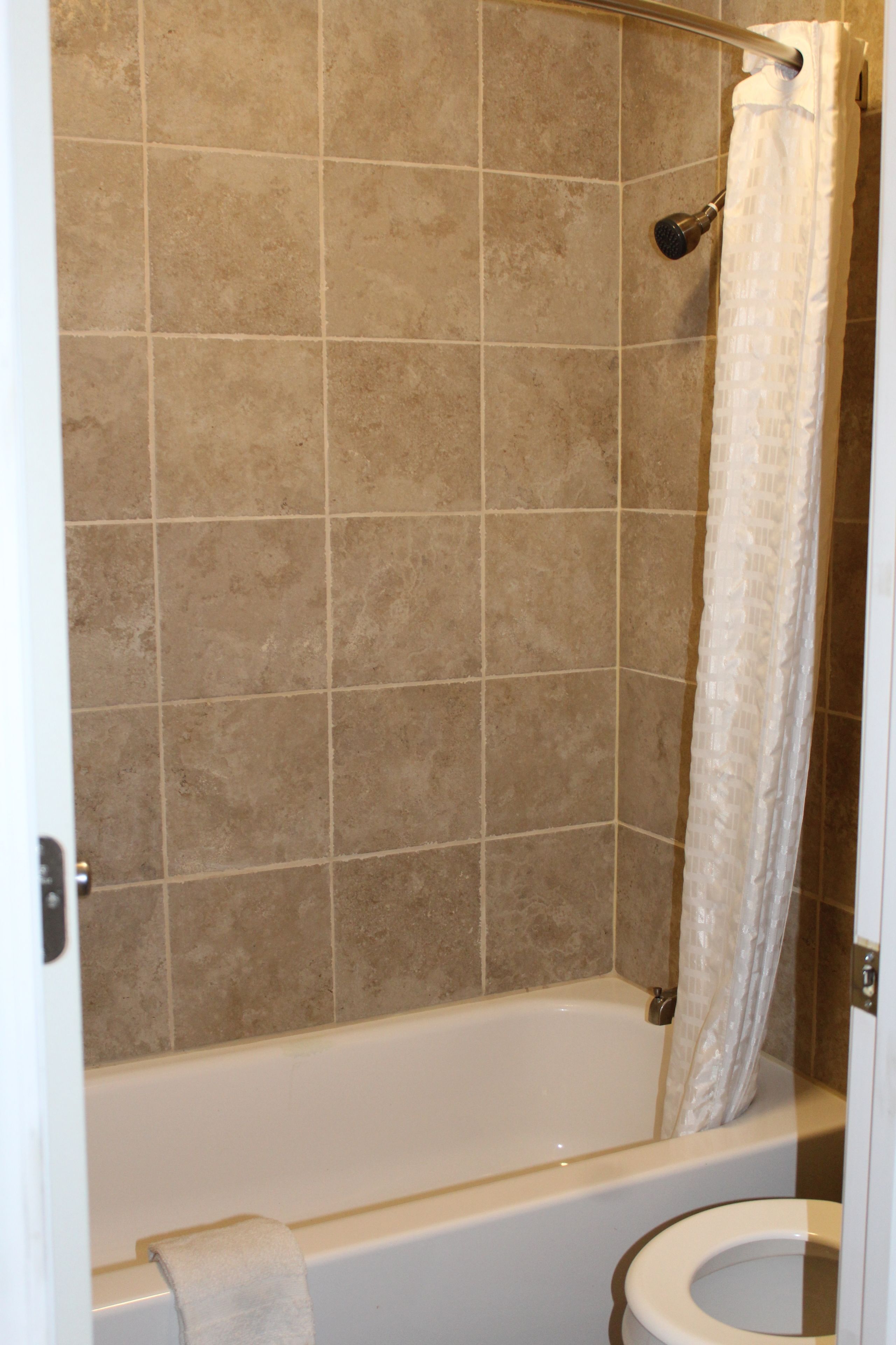 A bathroom with a bathtub, toilet, and shower curtain.
