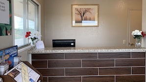 A reception area with a counter, framed artwork, and informational brochures. - Regency Inn (Rolla)