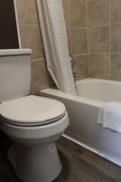 Un baño con inodoro, bañera y cortina de ducha.