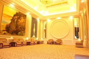 Un salón de conferencias con piso alfombrado, varias sillas dispuestas en filas y un cuadro grande en la pared.