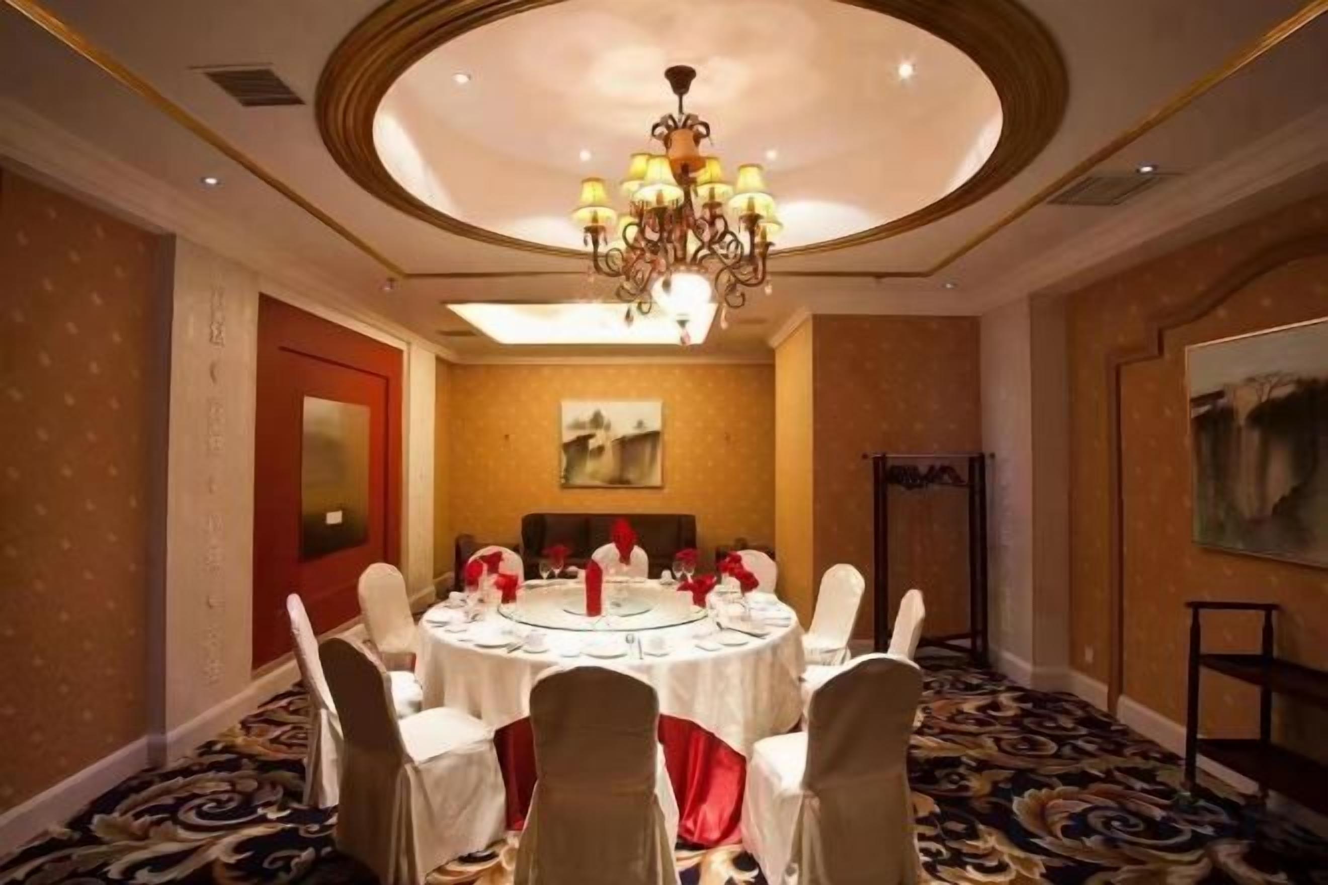 A conference room with a round table, white chairs, and a chandelier.