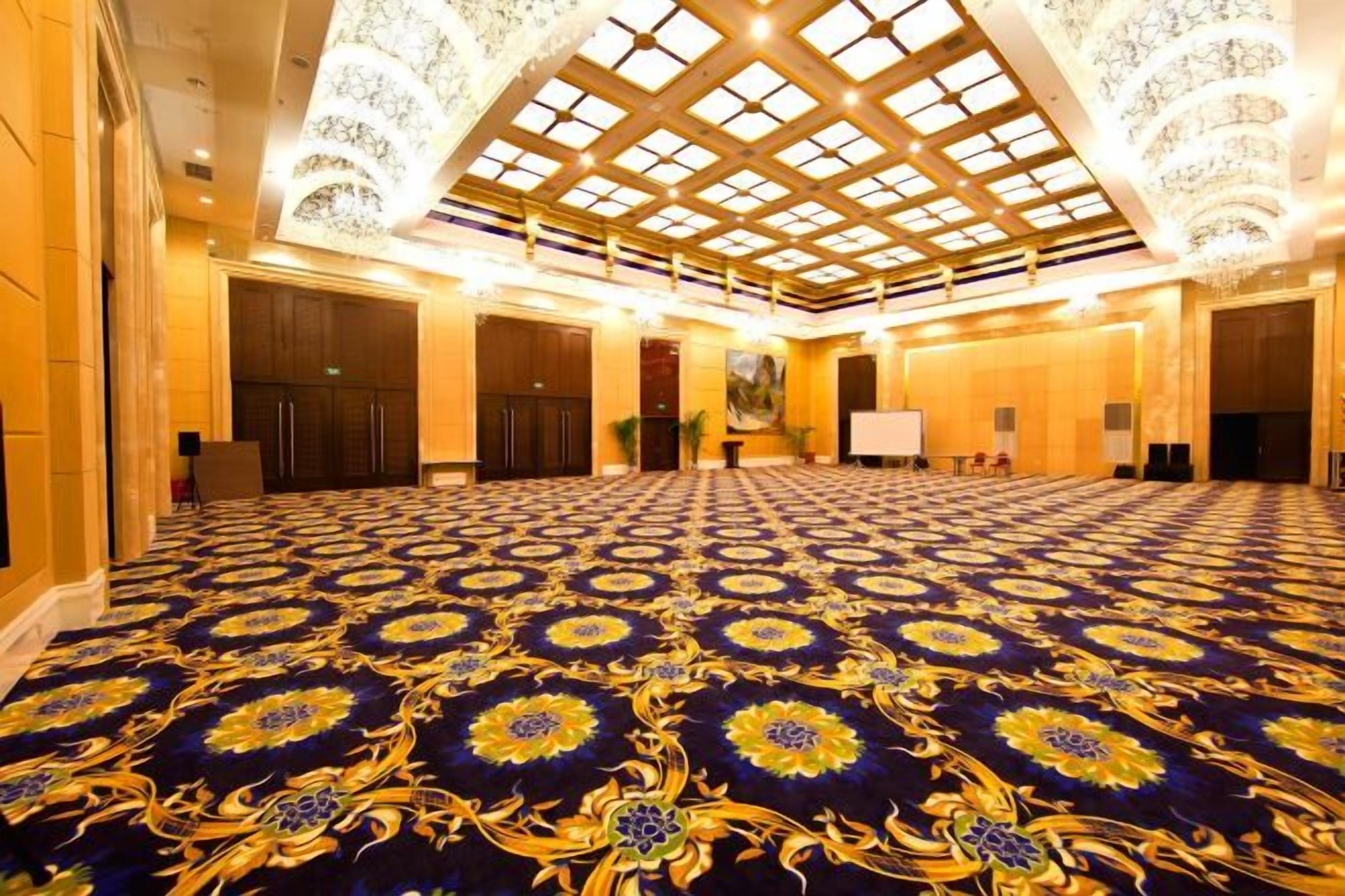 A large, well-lit room with a patterned carpet, a high ceiling with a skylight, and a chandelier.