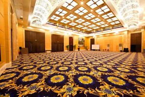 A large, well-lit room with a patterned carpet, a high ceiling with a skylight, and a chandelier.