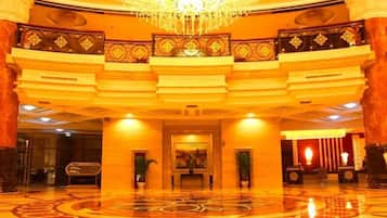 A grand lobby with a high ceiling, a large chandelier, and a patterned floor.