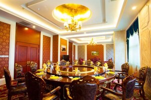 Un comedor formal con una mesa redonda, sillas ornamentadas y un candelabro.