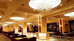 Un hall d’hôtel comprenant un comptoir d’accueil, plusieurs espaces de détente et des lustres.