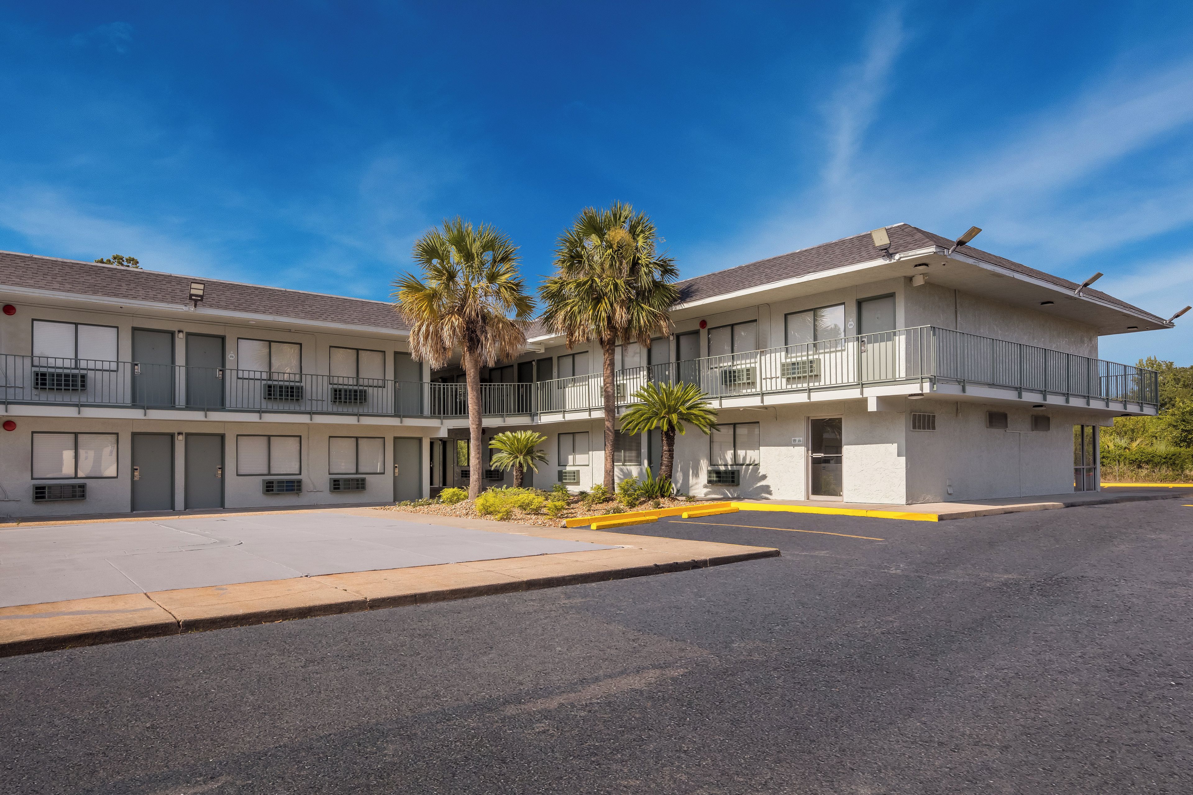 A motel with a two-story structure, multiple balconies, and a parking lot.