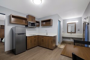 Une cuisine moderne avec des meubles en bois, un réfrigérateur en acier inoxydable, un four à micro-ondes et un évier.