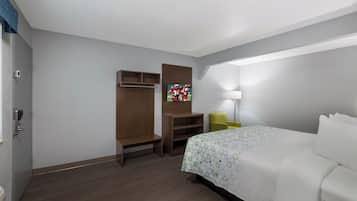 A hotel room with a bed, a desk, a chair, a TV, and a wardrobe.