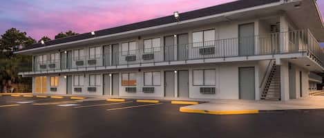 A motel with a flat roof, multiple windows, and a parking lot with marked spaces.