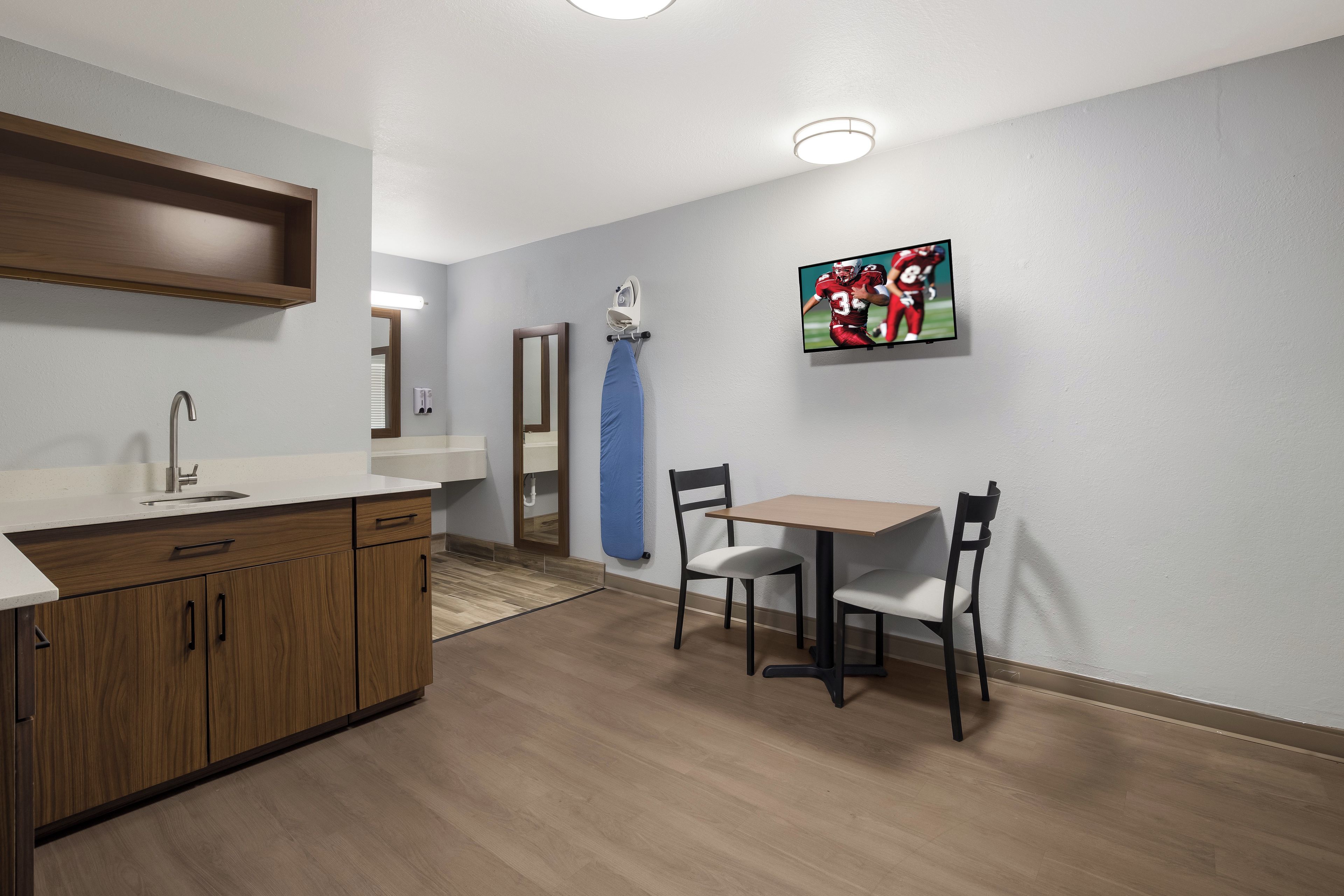 A modern kitchen with wooden cabinets, a sink, and a dining area with a table and chairs.
