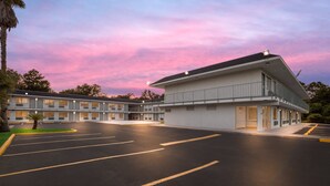 A motel with a large parking lot and a building with multiple windows and balconies.