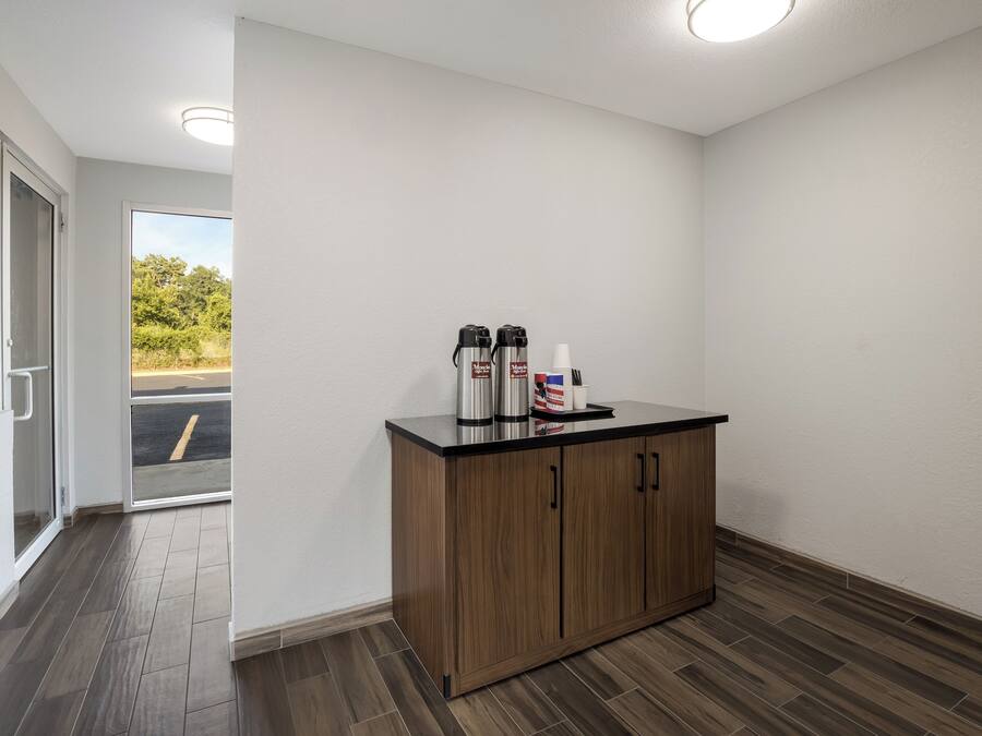 Une chambre propre et moderne, avec un meuble en bois, une machine à café et une tasse de café posée sur le comptoir.