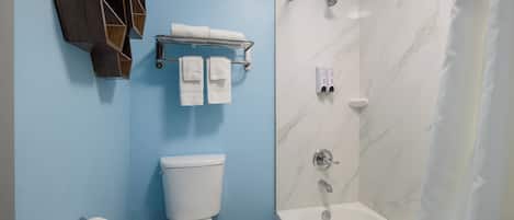 A bathroom with a toilet, a shower, a towel rack, and a toilet paper holder.