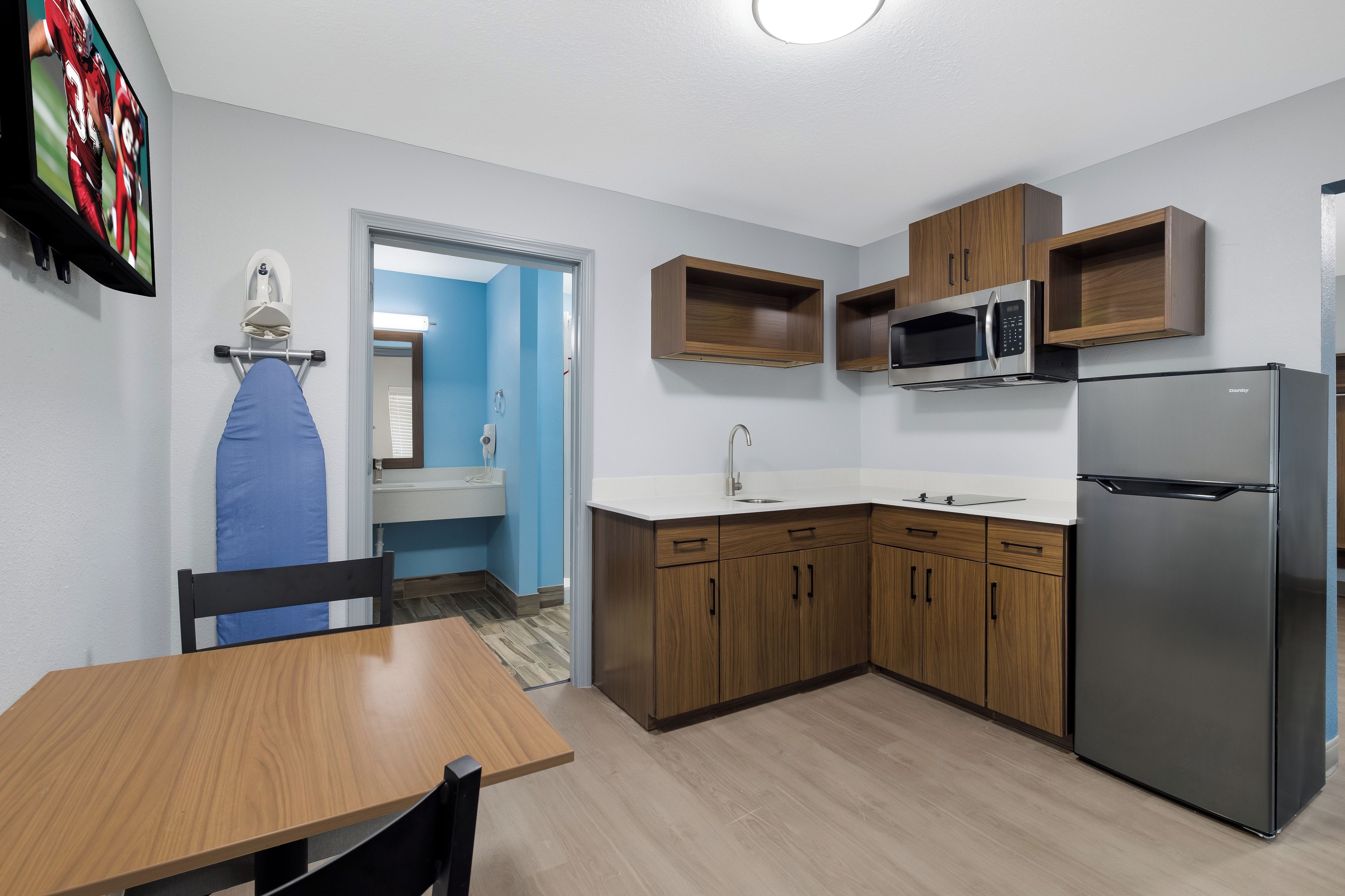 A compact kitchen with a refrigerator, microwave, and wooden cabinets.