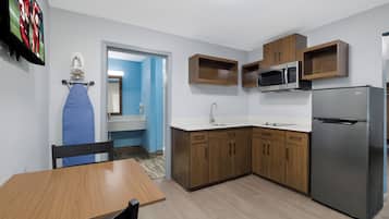 A compact kitchen with a refrigerator, microwave, and wooden cabinets.
