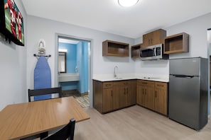 A compact kitchen with a refrigerator, microwave, and wooden cabinets.