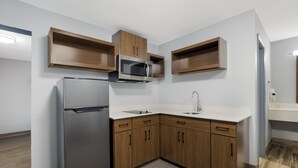 A modern kitchen with a built-in microwave, refrigerator, and wooden cabinets.