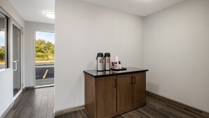 A clean, modern room with a wooden cabinet, a coffee machine, and a cup holder.